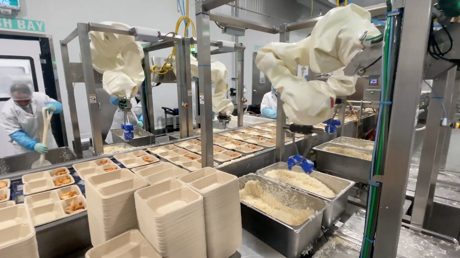 Chef Robotics' robots in action dispursing food into containers.