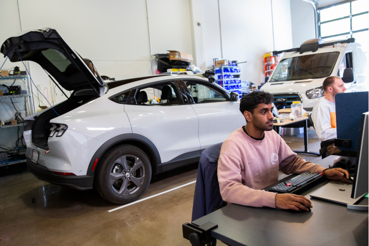 A Wayve engineer using Foxglove with a Wayve AV behind them.