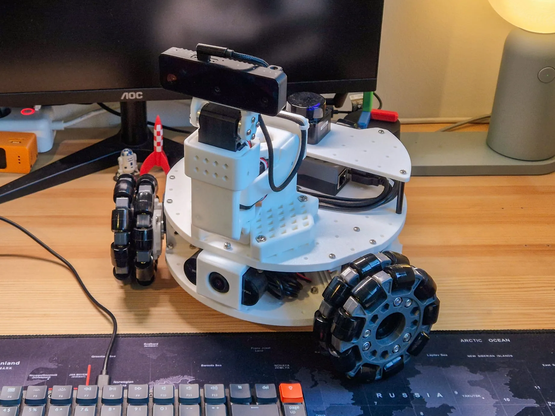 The LeKiwi mobile robot on a desk, with its pan-tilt camera, 360° LiDAR, and omni wheels